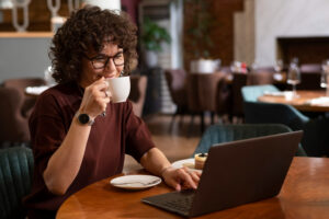 woman drinking coffee while checking laptop